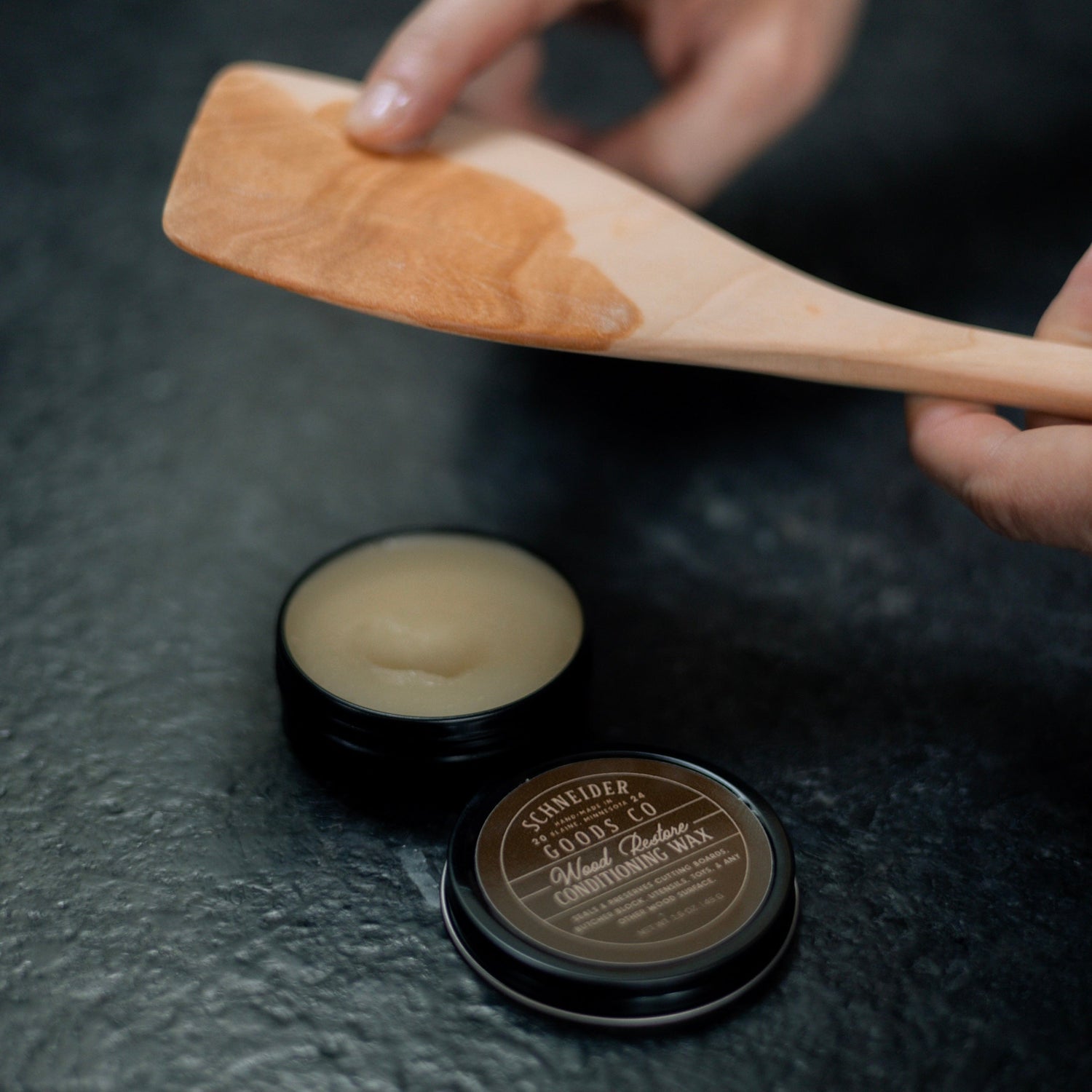 A wooden spatula being oiled with Schneider Goods Co Wood Restore.