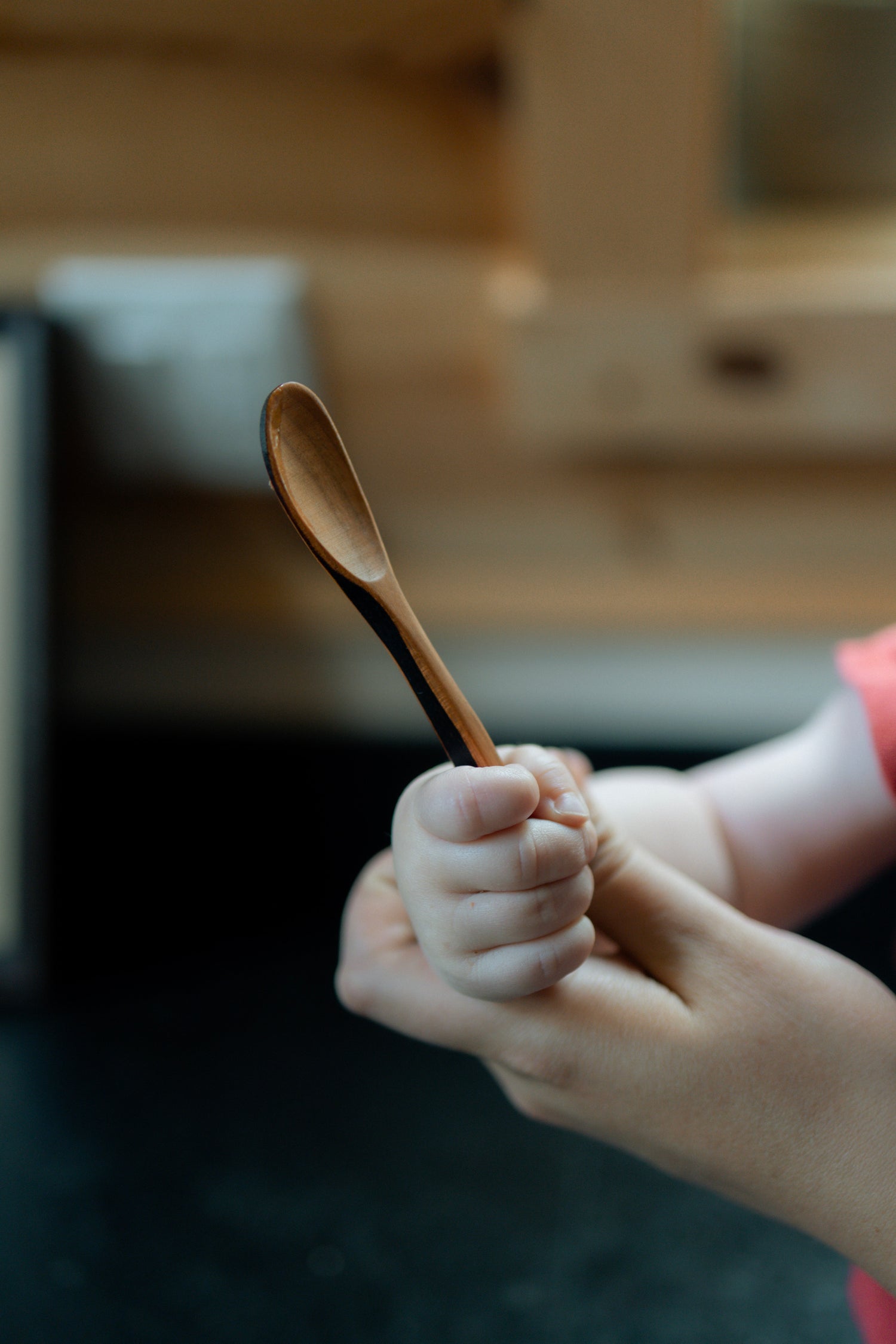 Baby holding wood spoon