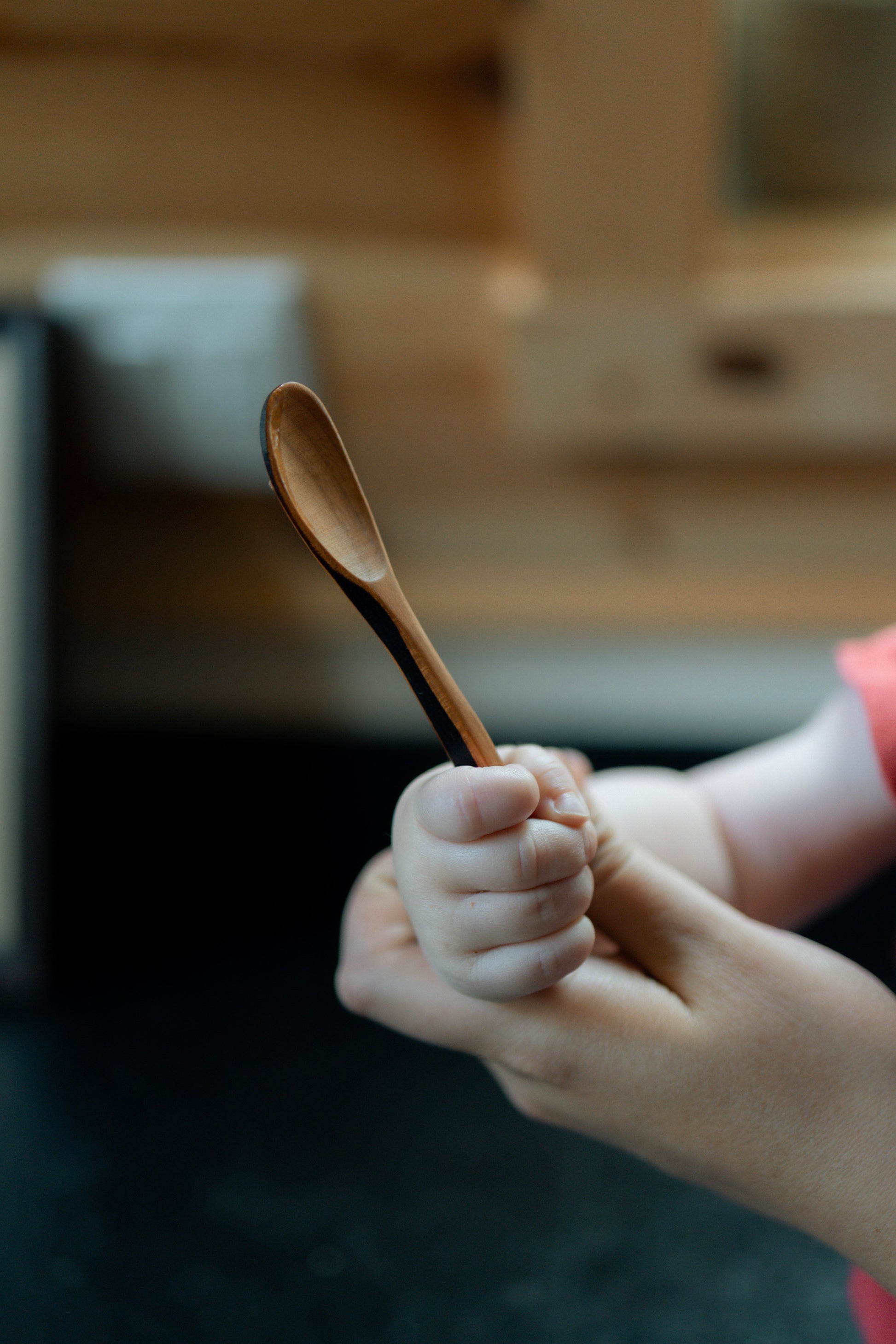 Baby holding wood spoon