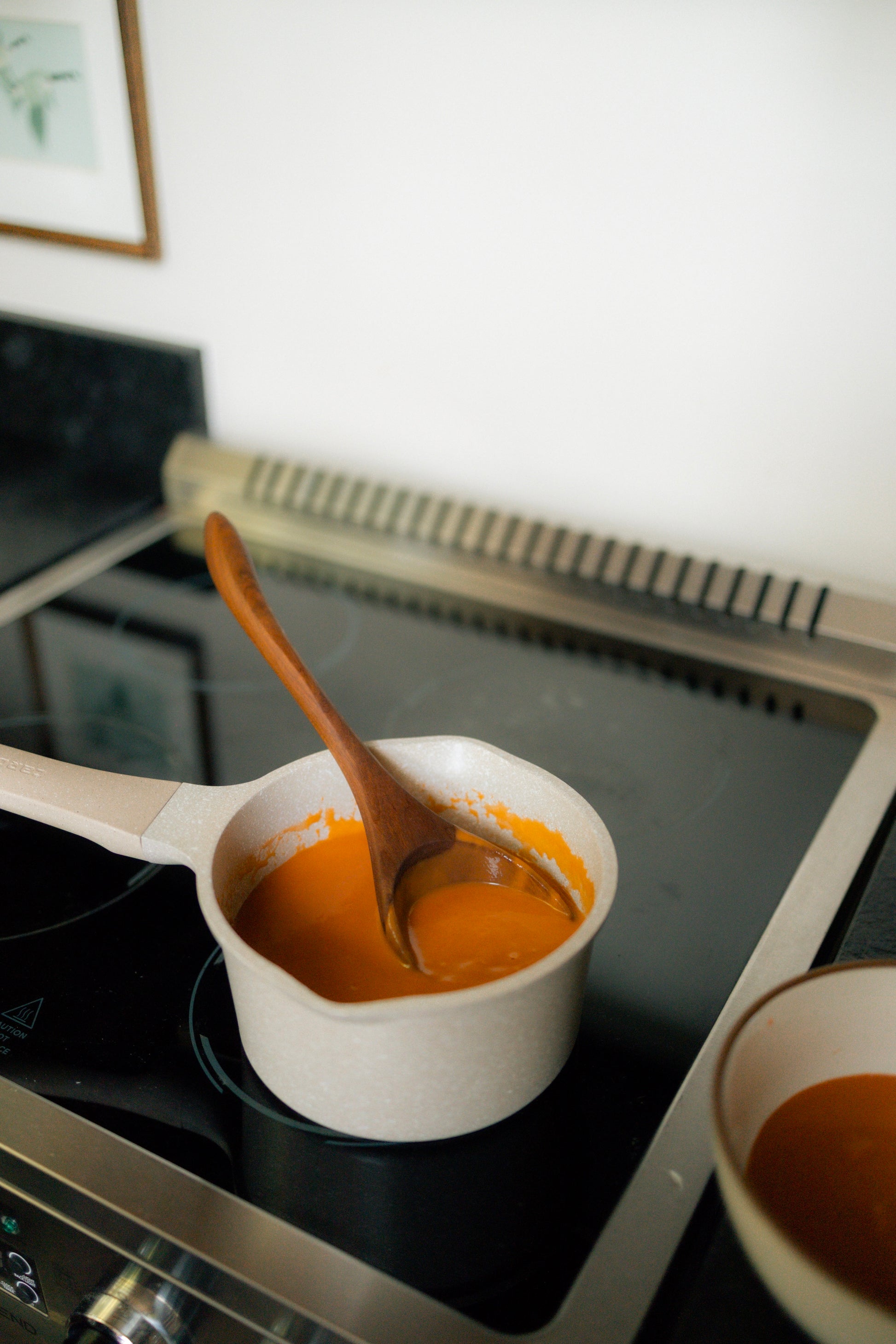 Cherry wood ladle in white pot on stove.