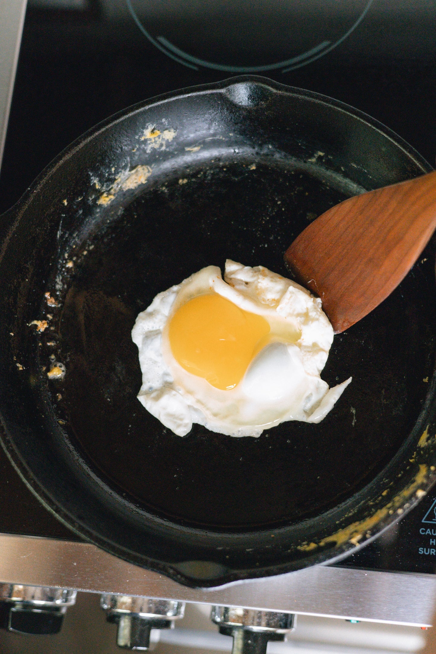 Egg and medium wood spatula in cast iron pan.