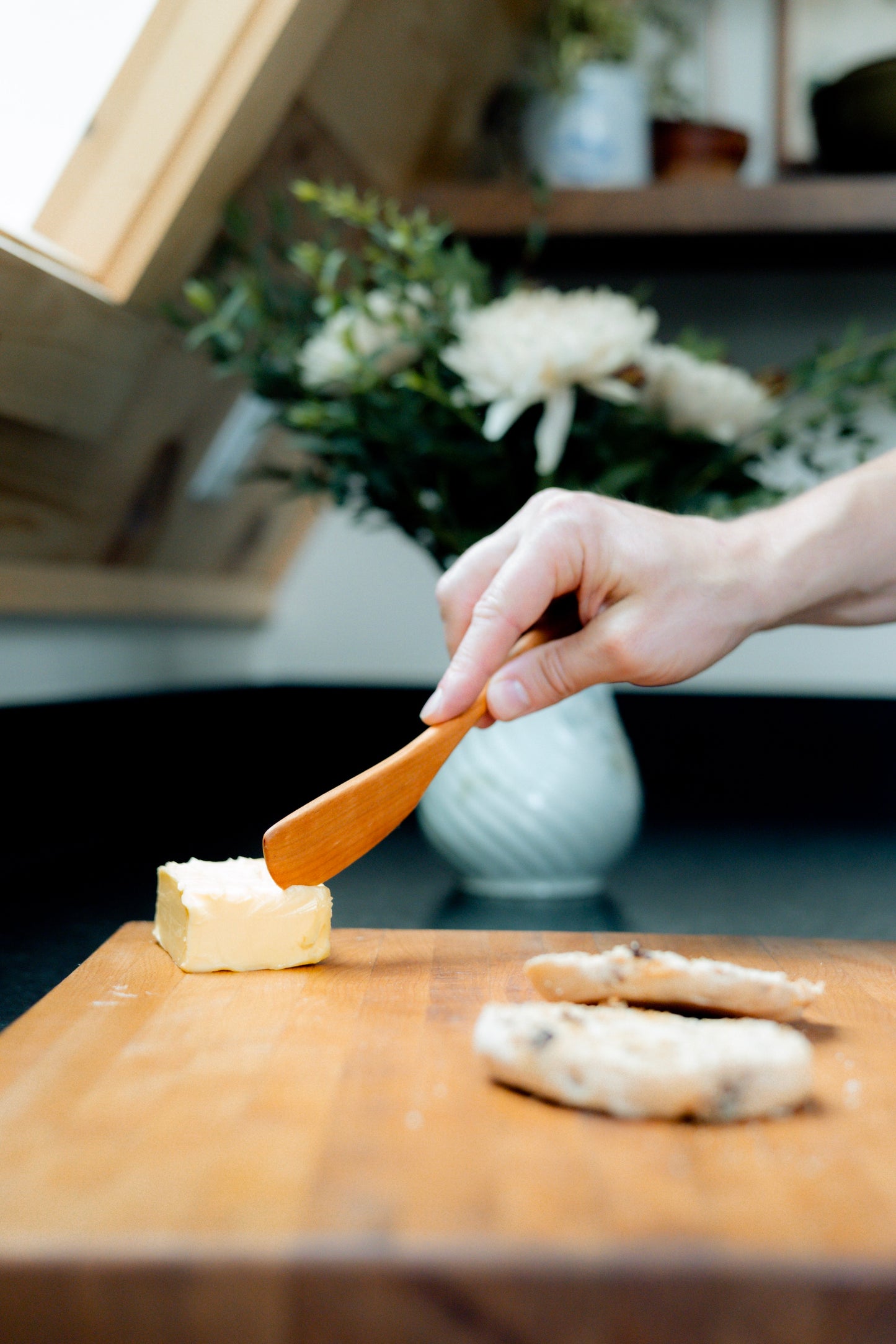 Cherry wood spreader putting butter on english muffin.