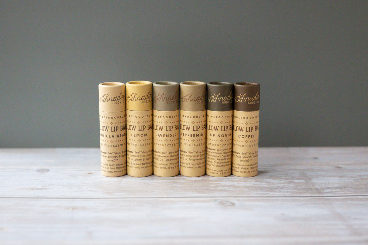 Tallow lip balms in large compostable tubes against a grey-green background.