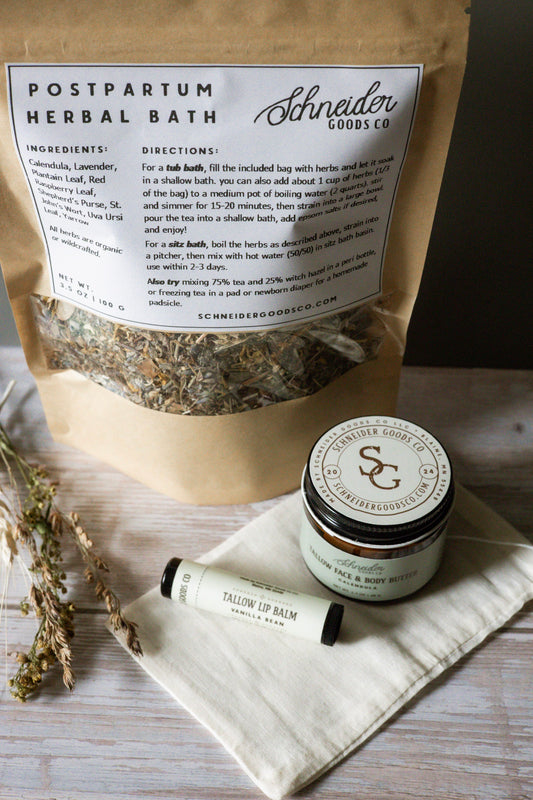 Postpartum herbal bath package with calendula tallow balm and vanilla bean tallow lip balm on a wooden surface
