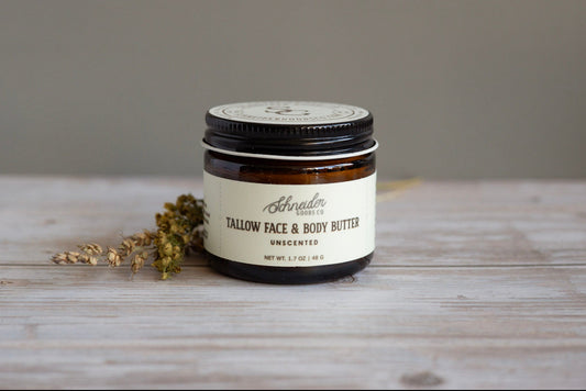 Jar of Schneider Goods Co Tallow Face & Body Butter on a wooden surface with a neutral background