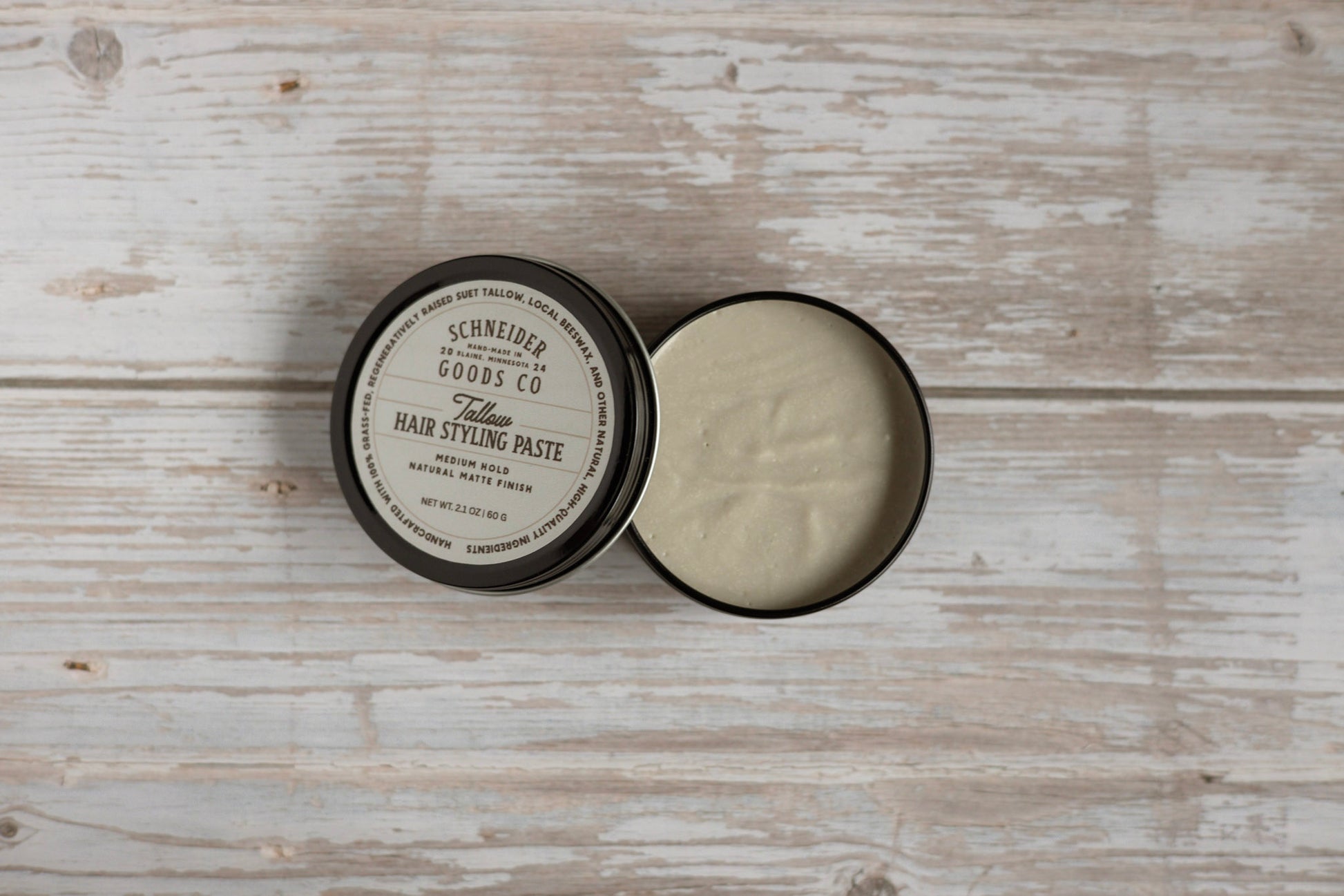 Tallow hair styling paste in a open container on a wooden surface