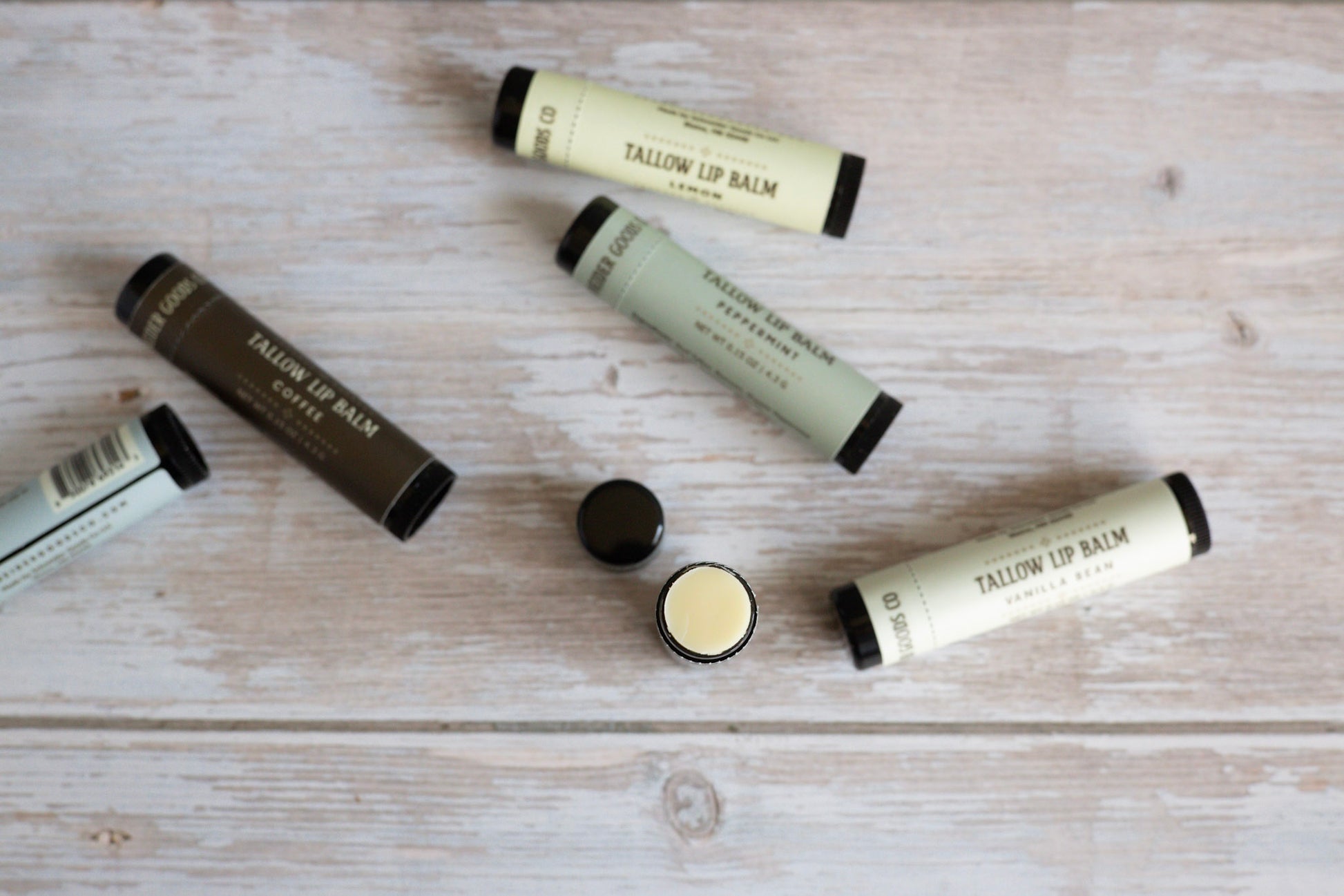 Multiple tallow lip balm tubes on a wooden surface