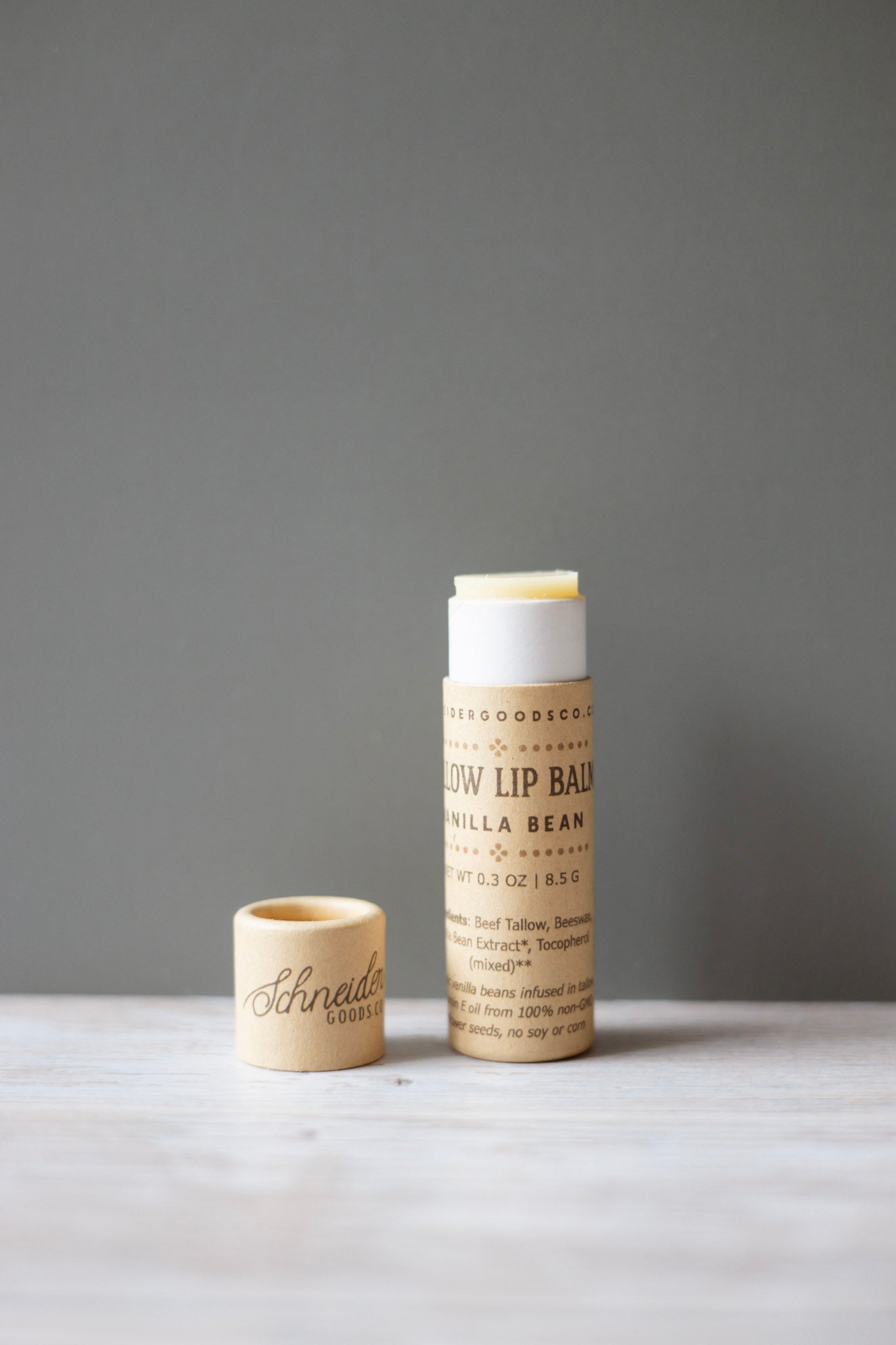 Two compostable tallow lip balm containers on a gray background