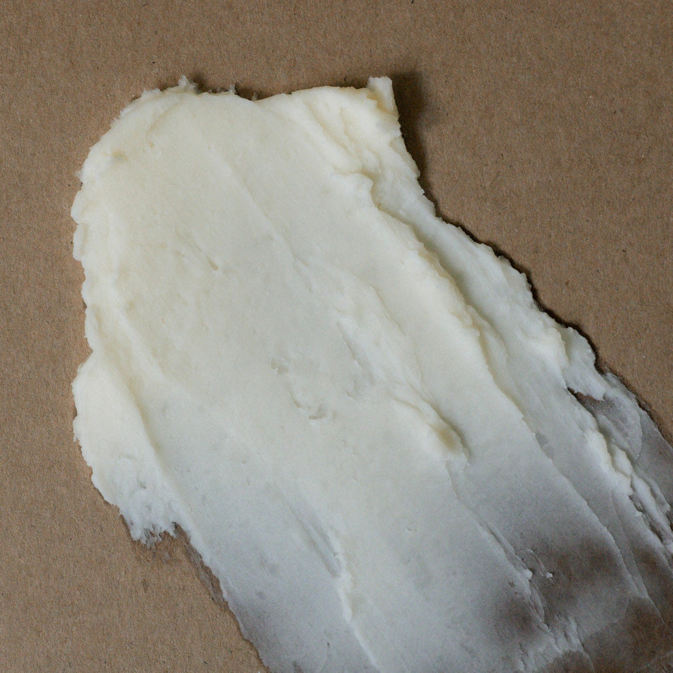 Creamy whipped tallow balm for face and body, on a paper brown background.